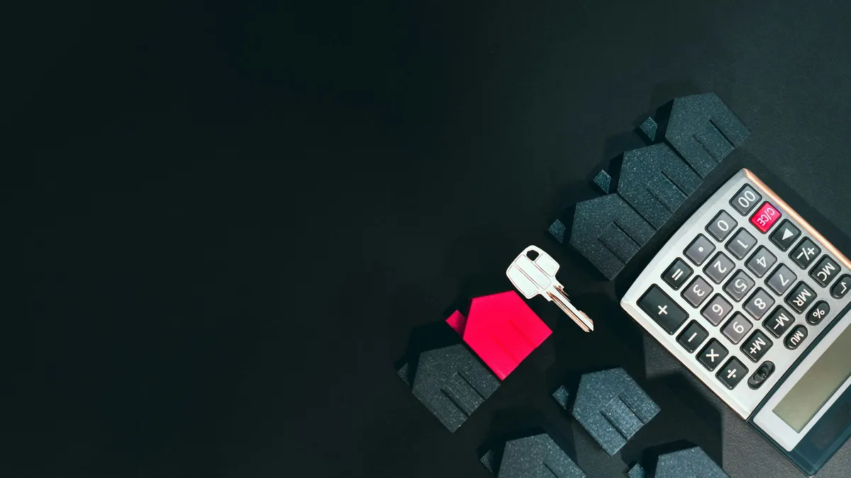 Een huismodel, sleutel en rekenmachine als illustratie van een verzekeringsbudget